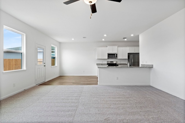 unfurnished living room featuring recessed lighting, light carpet, ceiling fan, and baseboards