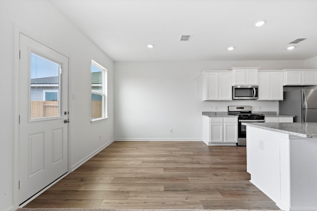 kitchen with white cabinets, light wood finished floors, visible vents, and stainless steel appliances