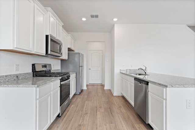 kitchen featuring light wood finished floors, visible vents, appliances with stainless steel finishes, white cabinetry, and a sink