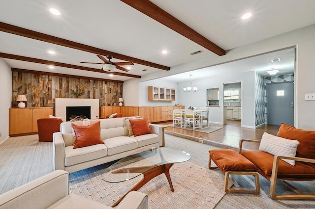 living room featuring recessed lighting, ceiling fan with notable chandelier, wood walls, visible vents, and beamed ceiling