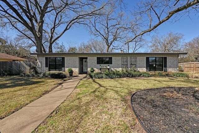 view of front of house with a front yard, brick siding, and fence