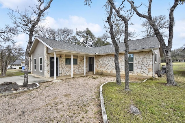 ranch-style house with stone siding, a shingled roof, a porch, and a front lawn