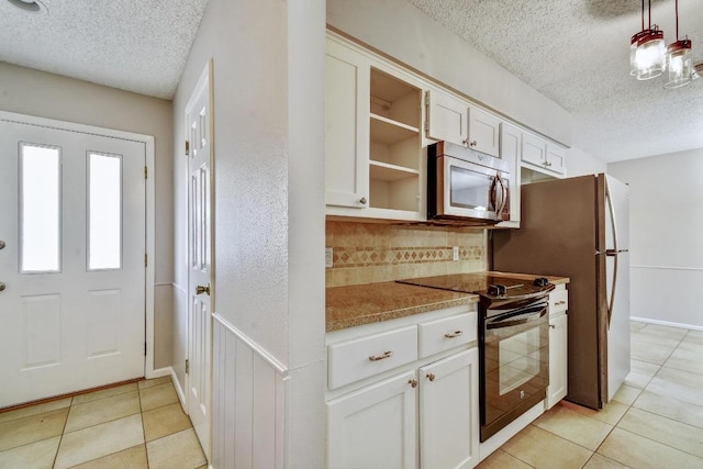 kitchen with a textured ceiling, black range with electric cooktop, white cabinetry, tasteful backsplash, and stainless steel microwave