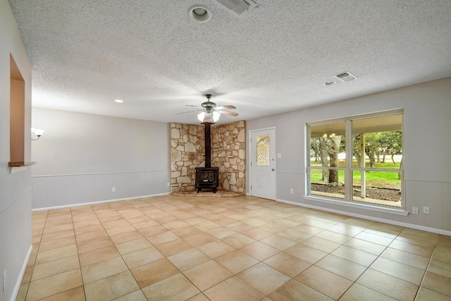 unfurnished living room featuring a wood stove, visible vents, and tile patterned floors