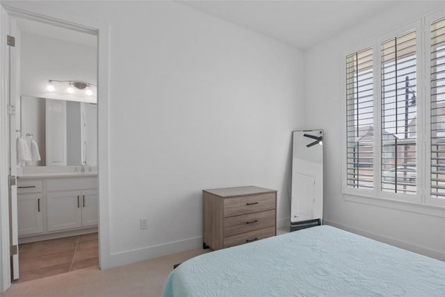 bedroom featuring light tile patterned floors, light carpet, a sink, ensuite bath, and baseboards