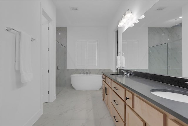 full bath with marble finish floor, a freestanding tub, a sink, and a marble finish shower