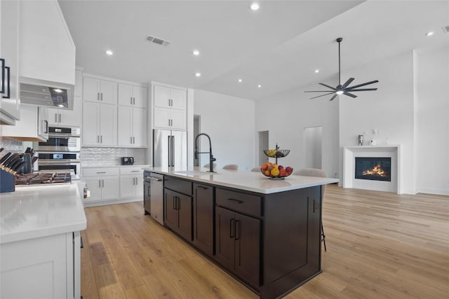 kitchen featuring light countertops, visible vents, a glass covered fireplace, white cabinets, and a sink