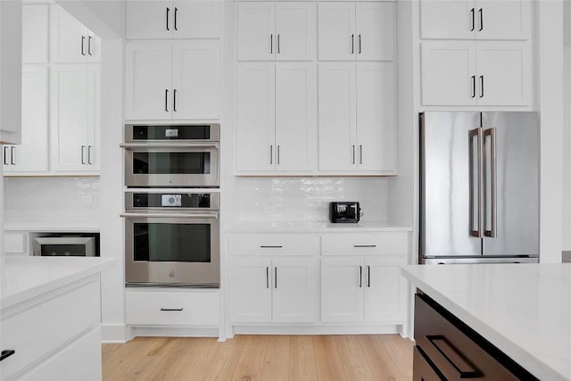 kitchen featuring white cabinets, light wood finished floors, appliances with stainless steel finishes, and light countertops