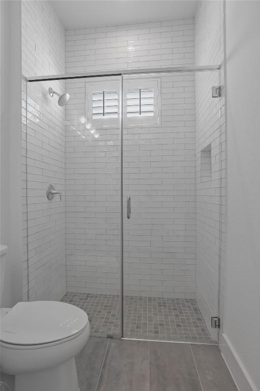 bathroom featuring a stall shower, toilet, and tile patterned floors