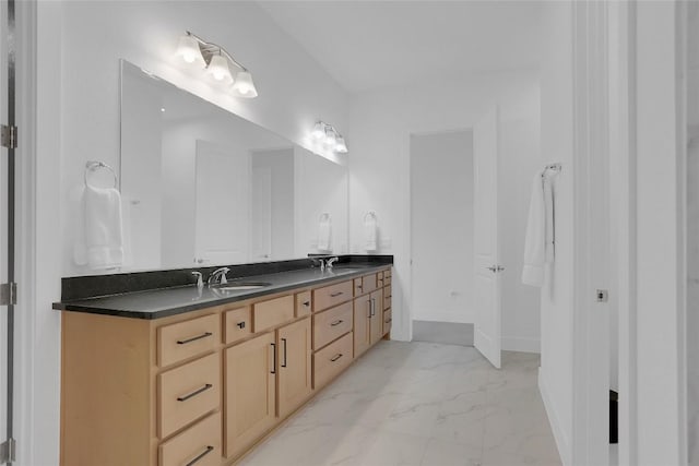 full bathroom with double vanity, marble finish floor, baseboards, and a sink