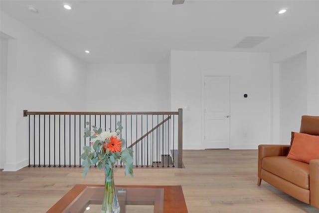 living area with recessed lighting, visible vents, wood finished floors, and an upstairs landing