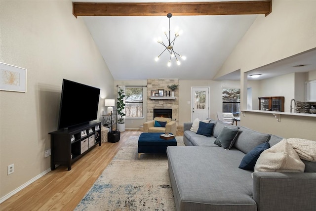 living area with light wood finished floors, a notable chandelier, a fireplace, and beamed ceiling