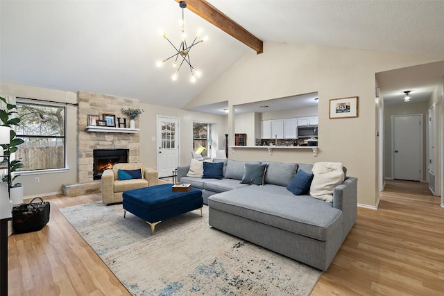 living room with high vaulted ceiling, a stone fireplace, light wood finished floors, beamed ceiling, and an inviting chandelier