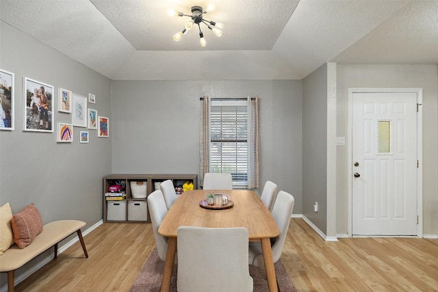 dining space with light wood finished floors, baseboards, and a textured ceiling