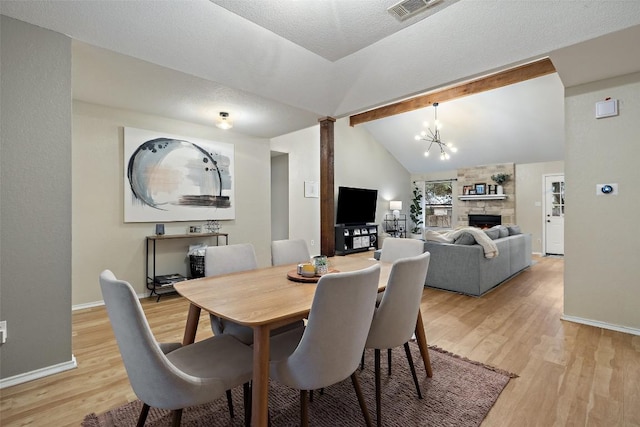 dining room with a chandelier, a fireplace, visible vents, light wood-style floors, and beam ceiling