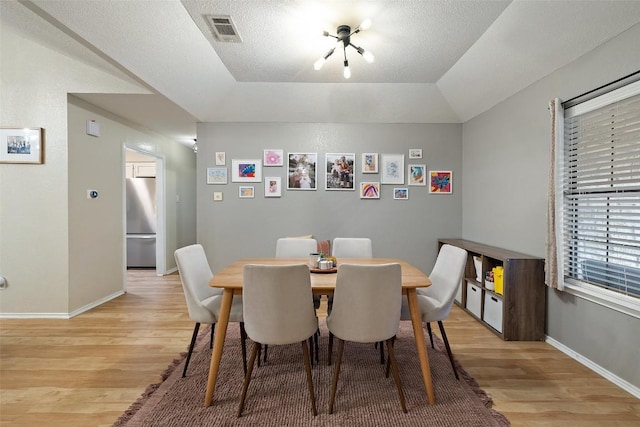 dining room featuring light wood-style flooring, visible vents, and baseboards