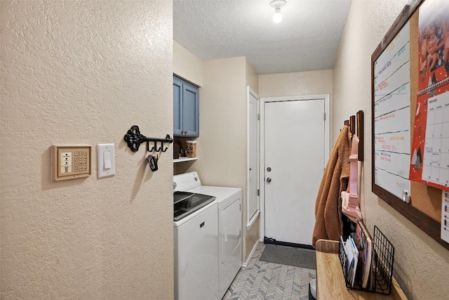 laundry area with a textured ceiling, a textured wall, cabinet space, and washer and dryer