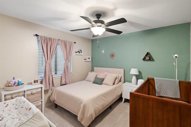 carpeted bedroom with a ceiling fan and a textured ceiling