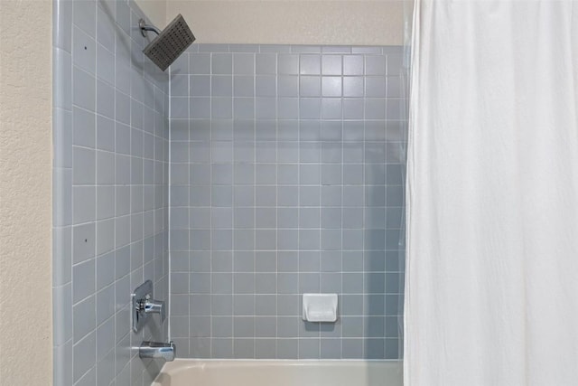 bathroom with a textured wall and shower / tub combo