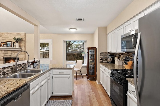 kitchen featuring stainless steel appliances, backsplash, a sink, and white cabinets