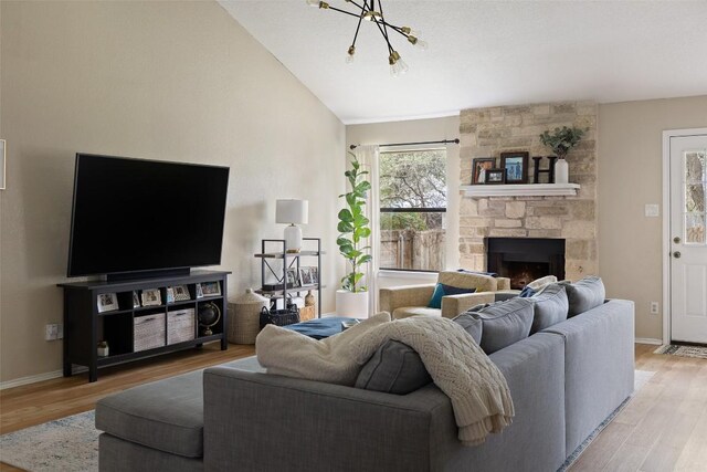 living room featuring lofted ceiling, light wood-style floors, a fireplace, and baseboards