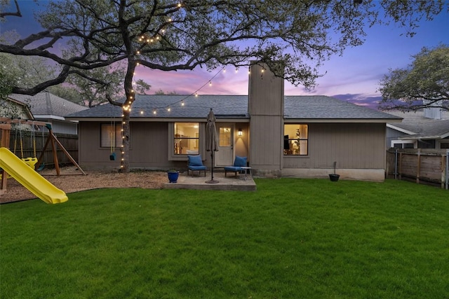 rear view of house featuring a playground, fence, a yard, a chimney, and a patio area