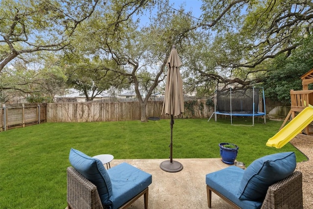 view of yard with a patio area, a fenced backyard, a trampoline, and a playground