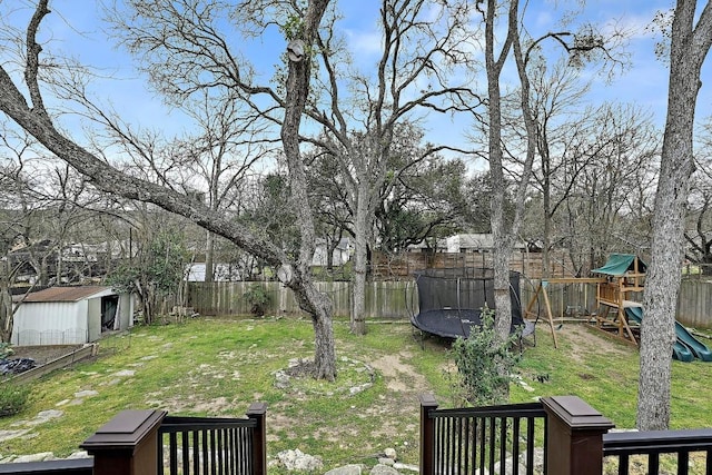 view of yard featuring an outbuilding, a trampoline, a playground, and a fenced backyard