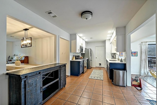 kitchen with light tile patterned floors, stainless steel appliances, visible vents, white cabinetry, and a sink