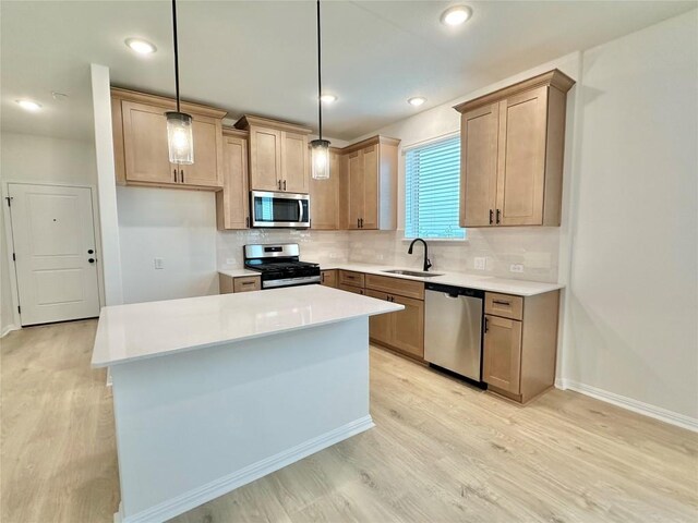 255 Glocken Ln, Kyle, TX 78640 - kitchen with stainless steel appliances, a sink, tasteful backsplash, light wood-style flooring, and a kitchen island