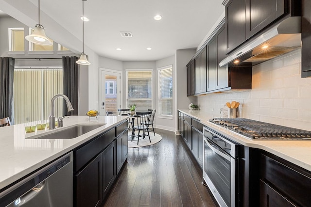 kitchen with under cabinet range hood, a sink, visible vents, appliances with stainless steel finishes, and decorative backsplash