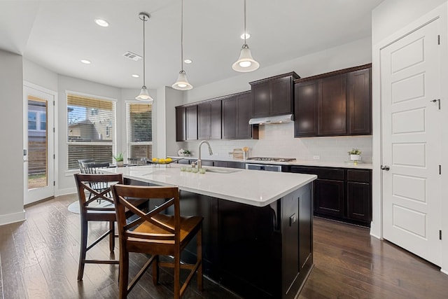 kitchen featuring tasteful backsplash, a breakfast bar area, visible vents, and dark wood-type flooring