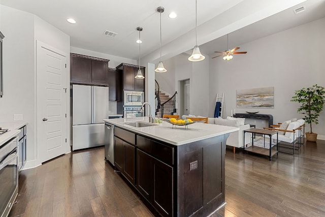 kitchen with dark brown cabinetry, dark wood finished floors, dishwasher, freestanding refrigerator, and a sink