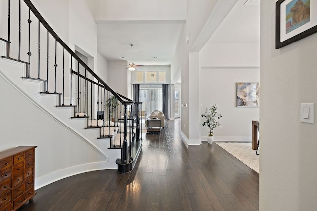 foyer with baseboards, a towering ceiling, hardwood / wood-style floors, and stairs