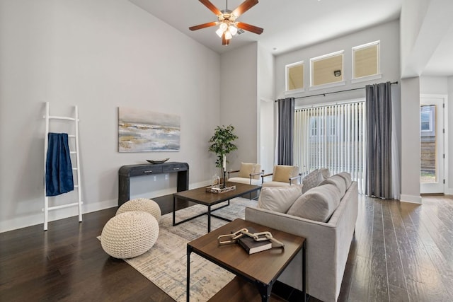 living area featuring a ceiling fan, baseboards, a high ceiling, and hardwood / wood-style flooring