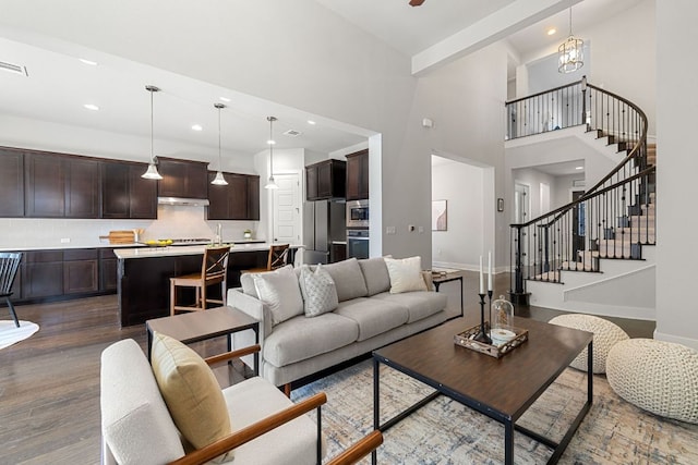 living area featuring recessed lighting, baseboards, stairway, dark wood finished floors, and an inviting chandelier