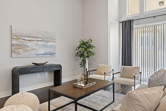 living room with a high ceiling, baseboards, and wood finished floors