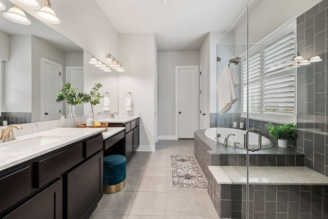 bathroom featuring a sink, a bath, tile patterned floors, double vanity, and a stall shower