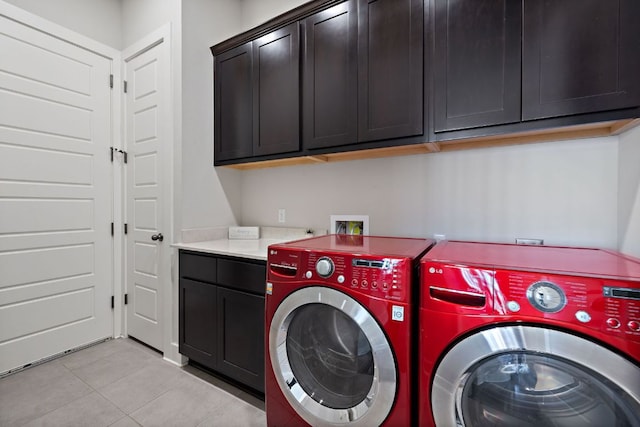 clothes washing area with cabinet space, washing machine and clothes dryer, and light tile patterned floors