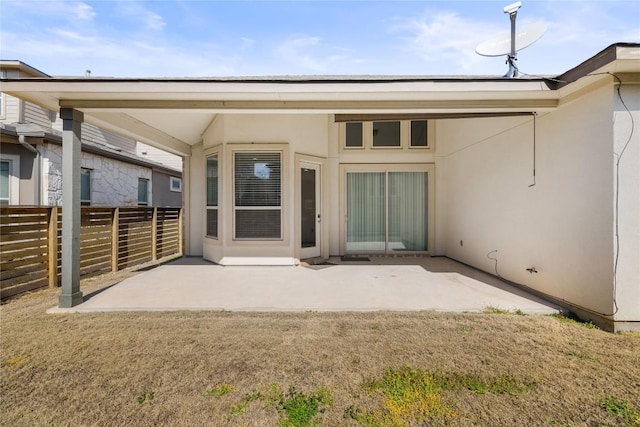 rear view of property featuring a patio area, fence, and stucco siding