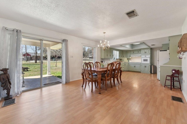 dining room with an inviting chandelier, visible vents, and light wood-style floors