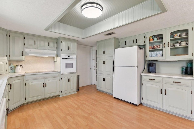 kitchen with visible vents, light countertops, light wood-style flooring, white appliances, and under cabinet range hood