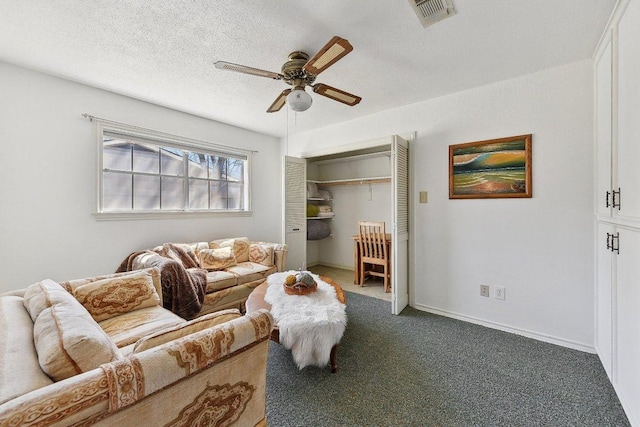 living area with baseboards, visible vents, a ceiling fan, a textured ceiling, and carpet floors