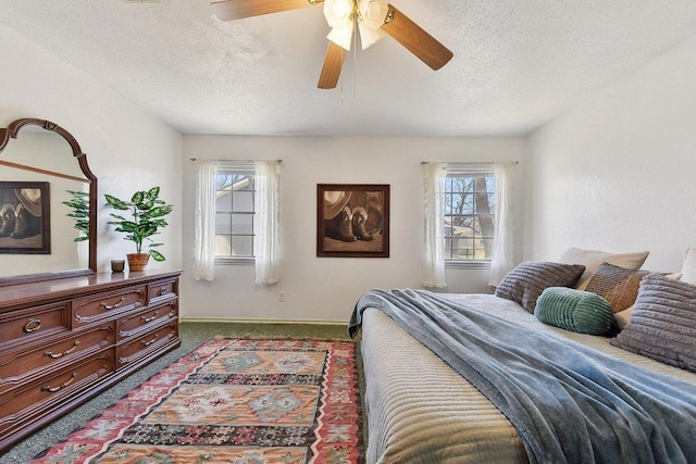 carpeted bedroom featuring ceiling fan, multiple windows, baseboards, and a textured ceiling