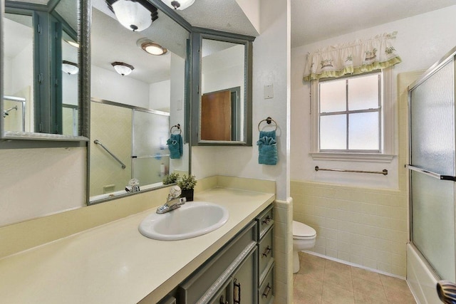 bathroom featuring tile walls, vanity, toilet, and tile patterned floors