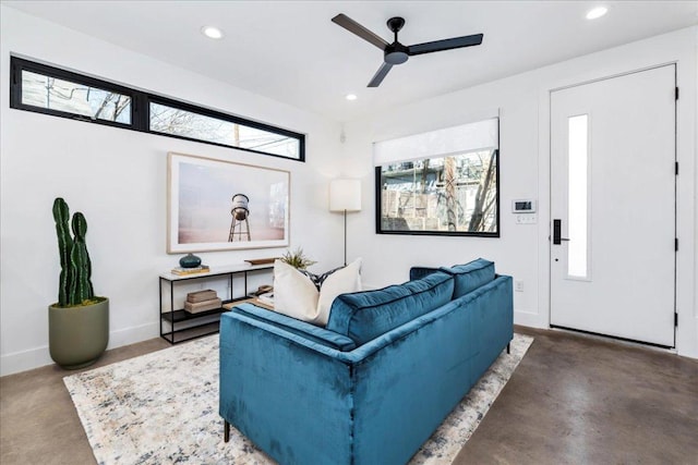 living area featuring concrete floors, baseboards, a ceiling fan, and recessed lighting