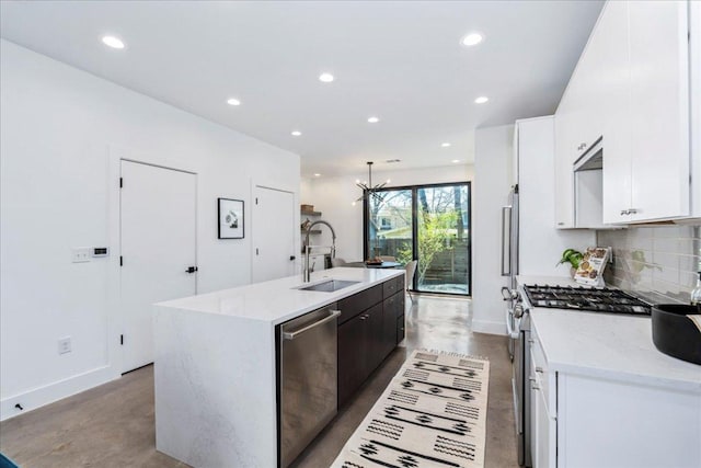 kitchen with a center island with sink, decorative backsplash, appliances with stainless steel finishes, white cabinets, and a sink