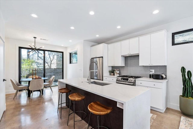 kitchen featuring visible vents, decorative backsplash, a breakfast bar area, stainless steel appliances, and concrete flooring