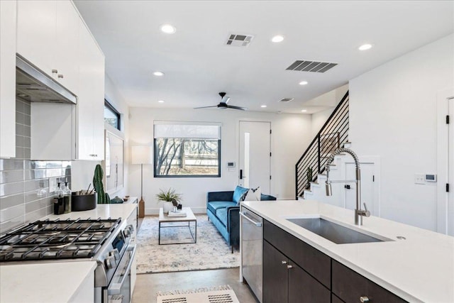 kitchen with a sink, visible vents, light countertops, appliances with stainless steel finishes, and decorative backsplash