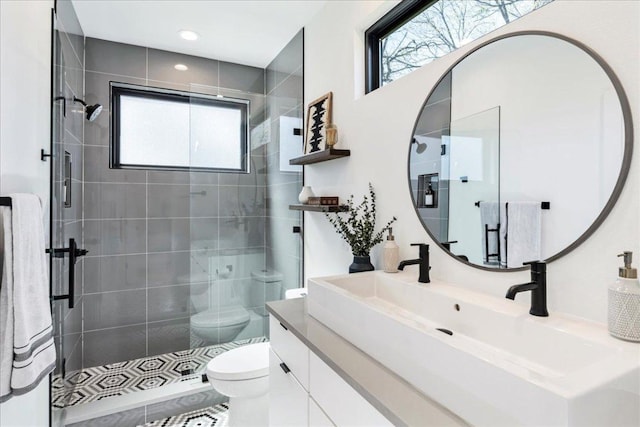 bathroom featuring toilet, a stall shower, a wealth of natural light, and vanity